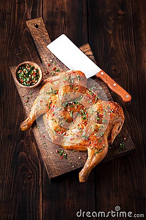 Grilled fried roast chicken tobacco on cutting board on dark wooden background Stock Photo