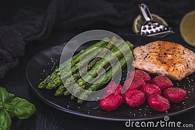 Grilled green asparagus and salmon with beetroot gnocchi Stock Photo