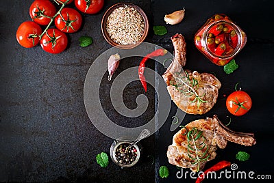 Grilled juicy steak on the bone with vegetables on a dark background. Stock Photo