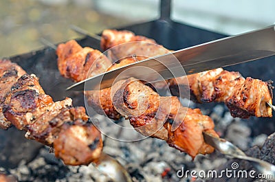 Grilled kebab frying on metal skewers. Roasted meat cooked at barbecue with smoke. Close up Stock Photo