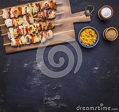 Grilled kebabs with peppers, pork and pineapple on a cutting board sauce and seasonings border place for text Stock Photo