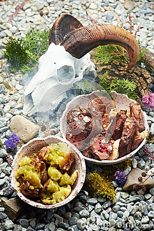 Grilled meat with boiled potatoes on a rocks with skull Stock Photo