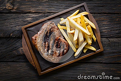 Grilled meat and fries presented enticingly on a wooden table Stock Photo