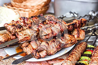 Grilled meat kebabs on the white plate. Skewered on wooden sticks tasty pork meat. Shashlik or Shish kebab. Stock Photo