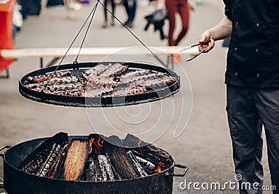 Grilled meat. man holding steel tongues and roasting beef pork o Stock Photo