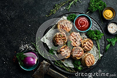 Grilled medallions wrapped in bacon. in a pan, ready to eat. On a black concrete background. Stock Photo