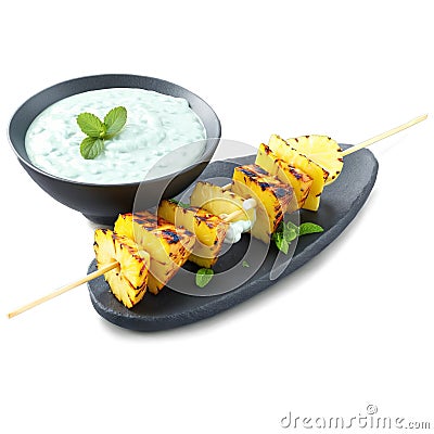 Grilled pineapple and halloumi skewers with a mint yogurt sauce and lemon wedges on clear Stock Photo