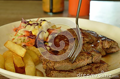 Grilled pork neck steak stabbing by silver fork with french fries and salad dressing mayonnaise on plate dipping spicy sauce Stock Photo