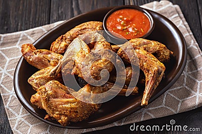 Grilled rabbit legs with spicy tomato dip. Stock Photo