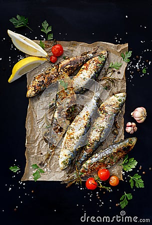 Grilled sardines on paper and a black background, top view. Stock Photo