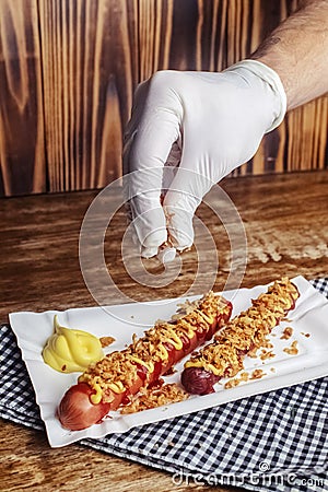 Grilled sausages closeup. The meat dish is sprinkled with dried caramelized onions. Top with grated cheese, mustard and ketchup. Stock Photo