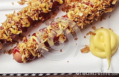 Grilled sausages closeup. The meat dish is sprinkled with dried caramelized onions. Top with grated cheese, mustard and ketchup. Stock Photo