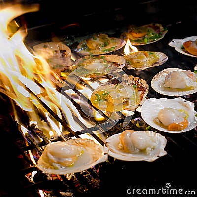 Grilled scallops topped with butter, garlic and parsley on flami Stock Photo