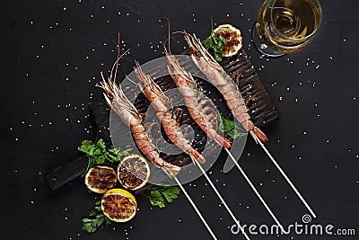 Grilled shrimp skewers. Seafood, shellfish. Shrimps Prawns skewers with herbs, garlic and lemon on black stone Stock Photo