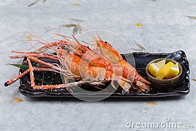 Grilled shrimps Giant Tiger Pawn with salt served with sliced lemon in black stone plate on washi Japanese paper Stock Photo