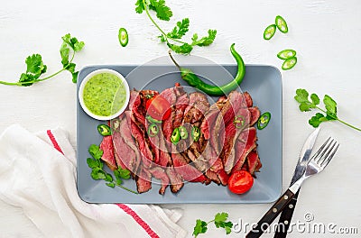Grilled and sliced rare beef skirt steak served with green chimichurri sauce Stock Photo