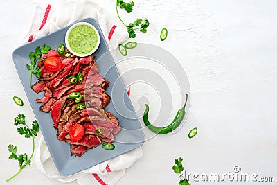 Grilled and sliced rare beef skirt steak served with green chimichurri sauce Stock Photo