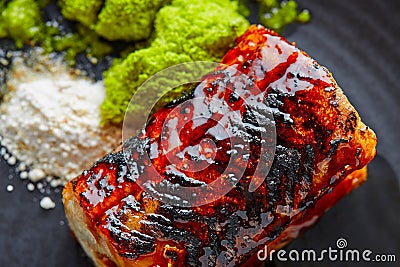 Grilled smoked eel on black plate Stock Photo