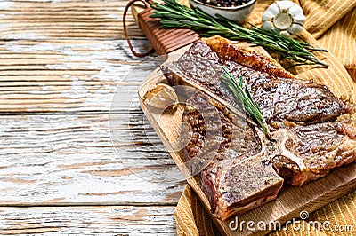 Grilled T bone steak on a chopping Board. Cooked tbone beef. White wooden background. Top view. Copy space Stock Photo