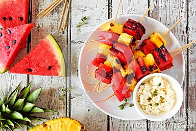 Grilled summer watermelon and pineapple fruit kabobs with feta, top view over white wood Stock Photo