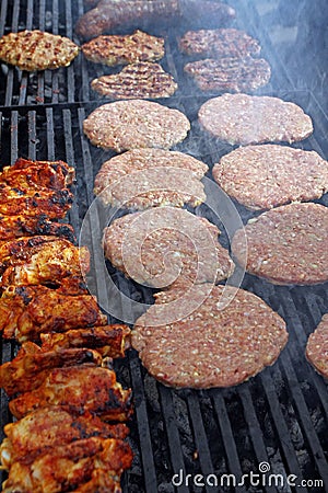 Grilling sausages, burgers, pork steak on barbecues gas grill for party. Hot dogs,sausages and hamburgers on a barbeque, bbq. Smok Stock Photo