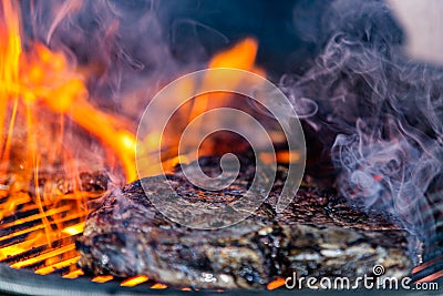 Grilling steaks on flaming gril Stock Photo
