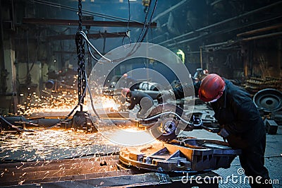 Grinding in a steel factory. Worker with a big saw cutting metal. Stock Photo