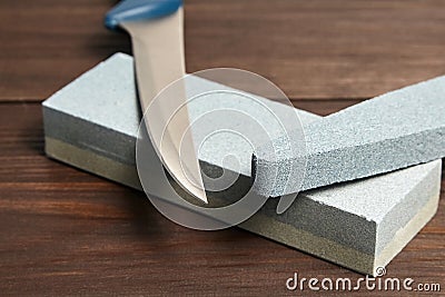 Grindstones. Two whetstones and steel knife blade. Oval and rectangular double layer sharpening stone on wooden table Stock Photo