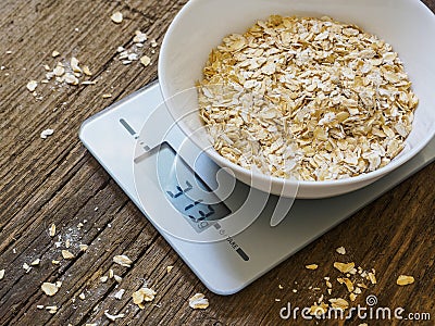 Grits in a white bowl on the kitchen scales on wooden background Stock Photo