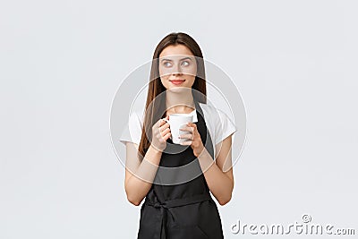 Grocery store employees, small business and coffee shops concept. Pleased cute saleswoman in black apron enjoying break Stock Photo