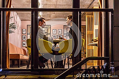 GRODNO, BELARUS - DECEMBER, 2018: loving couple at the table drinking coffee in interior in small modern pub cafe with loft design Editorial Stock Photo