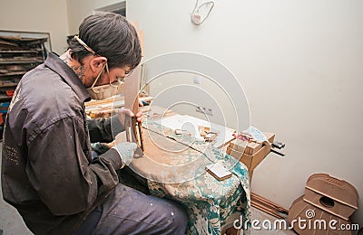 GRODNO, BELARUS - JANUARY 18, 2017. Serious professional guitar-maker working with unfinished guitar at workshop Editorial Stock Photo