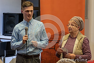 Grodno, Belarus, January 16, 2019: A young reporter holding a microphone. Conversation with an elderly man on stage. The retiree Editorial Stock Photo