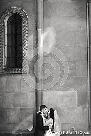 Grom huging kissing bride with red hair near wall outdoors Lviv Stock Photo