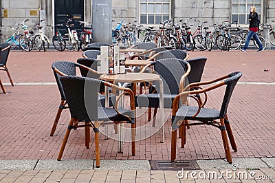 European cafe tables and wicker chairs on a brick-laid city street Editorial Stock Photo