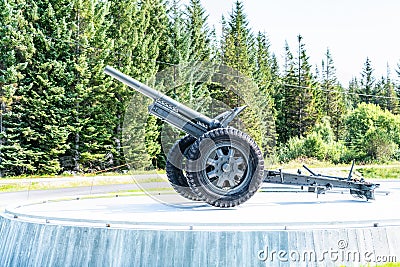 Gronsvik, Norway - August 06, 2019: Side view at artilery gun standing in front of Main building of museum of Gronsvik coastal Editorial Stock Photo