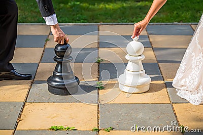 Groom and bride together on wedding day playing outdoor chess. Stock Photo