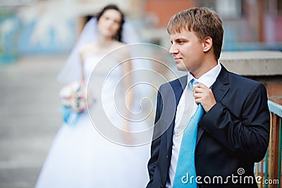 The groom dark blue suit straightens turquoise tie Stock Photo