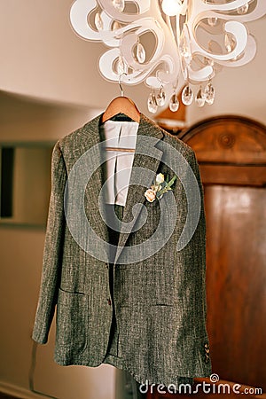 Groom gray jacket hangs on a chandelier in a hotel room Stock Photo