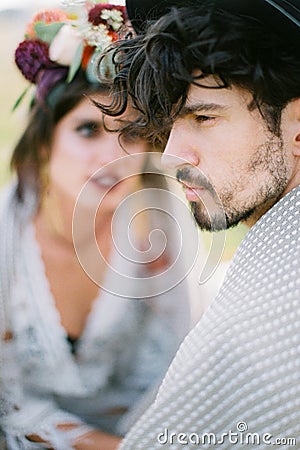 Groom in a hat and plaid sits next to bride in a wreath Stock Photo
