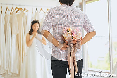 Groom hiding flower behind back in order to surprise bride,Woman positive emotion and face astonished happy and smling Stock Photo