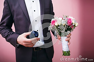 Groom holds wedding bouquet and velvet gift box Stock Photo