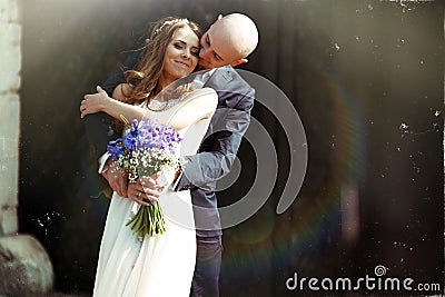 Groom kisses bride's cheek hugging her from behind in the rays o Stock Photo