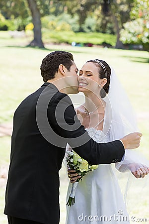 Groom kissing bride in garden Stock Photo