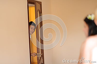 groom looking on a bride through the door Stock Photo