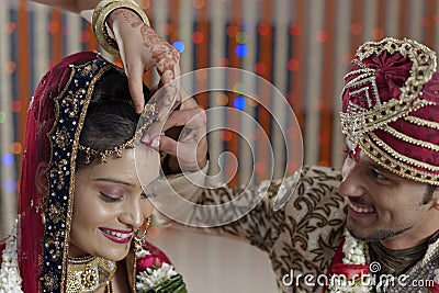 Groom putting Sindoor on Bride's forehead in Indian Hindu wedding. Stock Photo