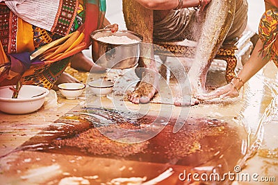 Family members pasting the turmeric powder haldi oil mixed with milk on groom`s feet and body Stock Photo