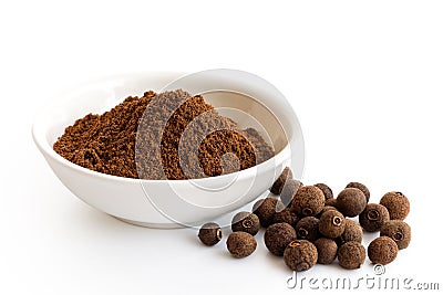 Ground allspice in white ceramic bowl isolated on white. Whole a Stock Photo