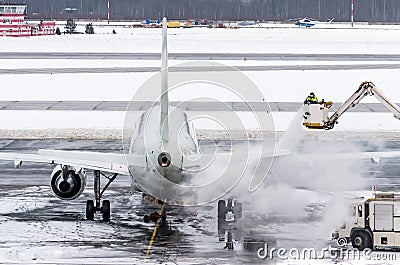 Ground crew provides de-icing. They are spraying the aircraft, which prevents the occurrence of frost. Stock Photo
