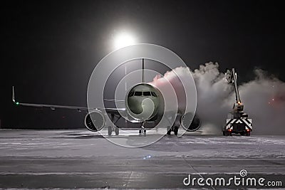 Ground deicing of a passenger airliner on the night airport apron at winter Stock Photo